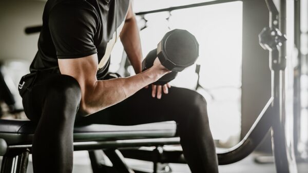 man doing concentration curls exercise working out with dumbbell