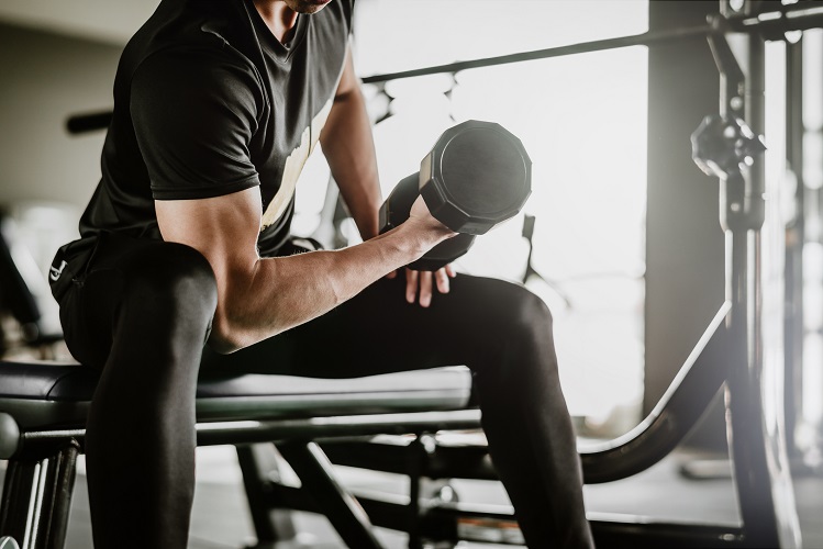 man doing concentration curls exercise working out with dumbbell